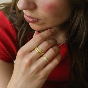 hand met gold plated stacking ringen met relief 
